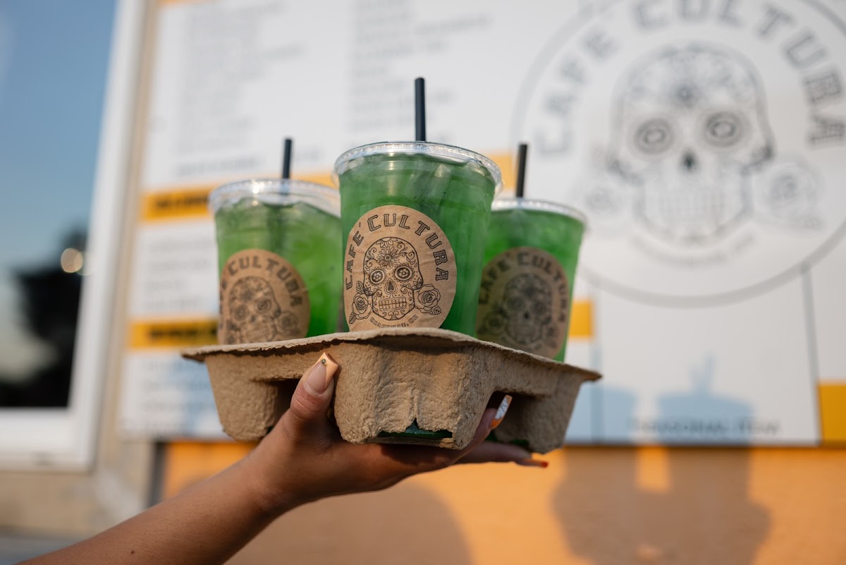 Three green refreshers in a carry tray with the Cafe Cultura logo behind
