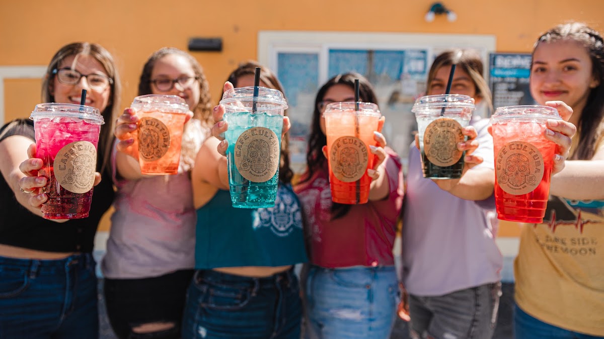 The Cafe Cultura crew holding out a lineup of colorful drinks